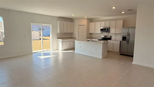 a kitchen with stainless steel appliances a sink a stove a refrigerator cabinets and a window