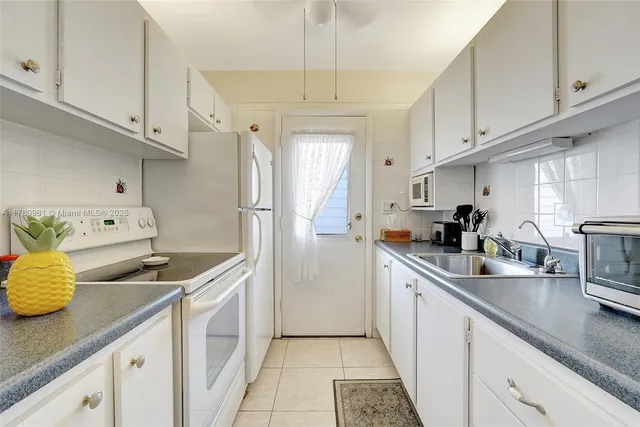 a kitchen with stainless steel appliances a sink a stove and white cabinets
