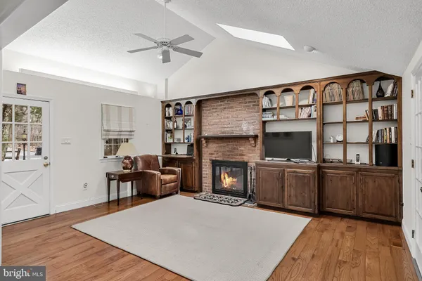 a living room with stainless steel appliances granite countertop furniture wooden floor and a fireplace