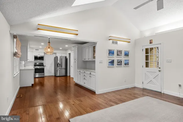 a view of a hallway with wooden floor and a kitchen