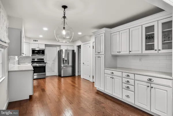 a large kitchen with white cabinets stainless steel appliances and wooden floor