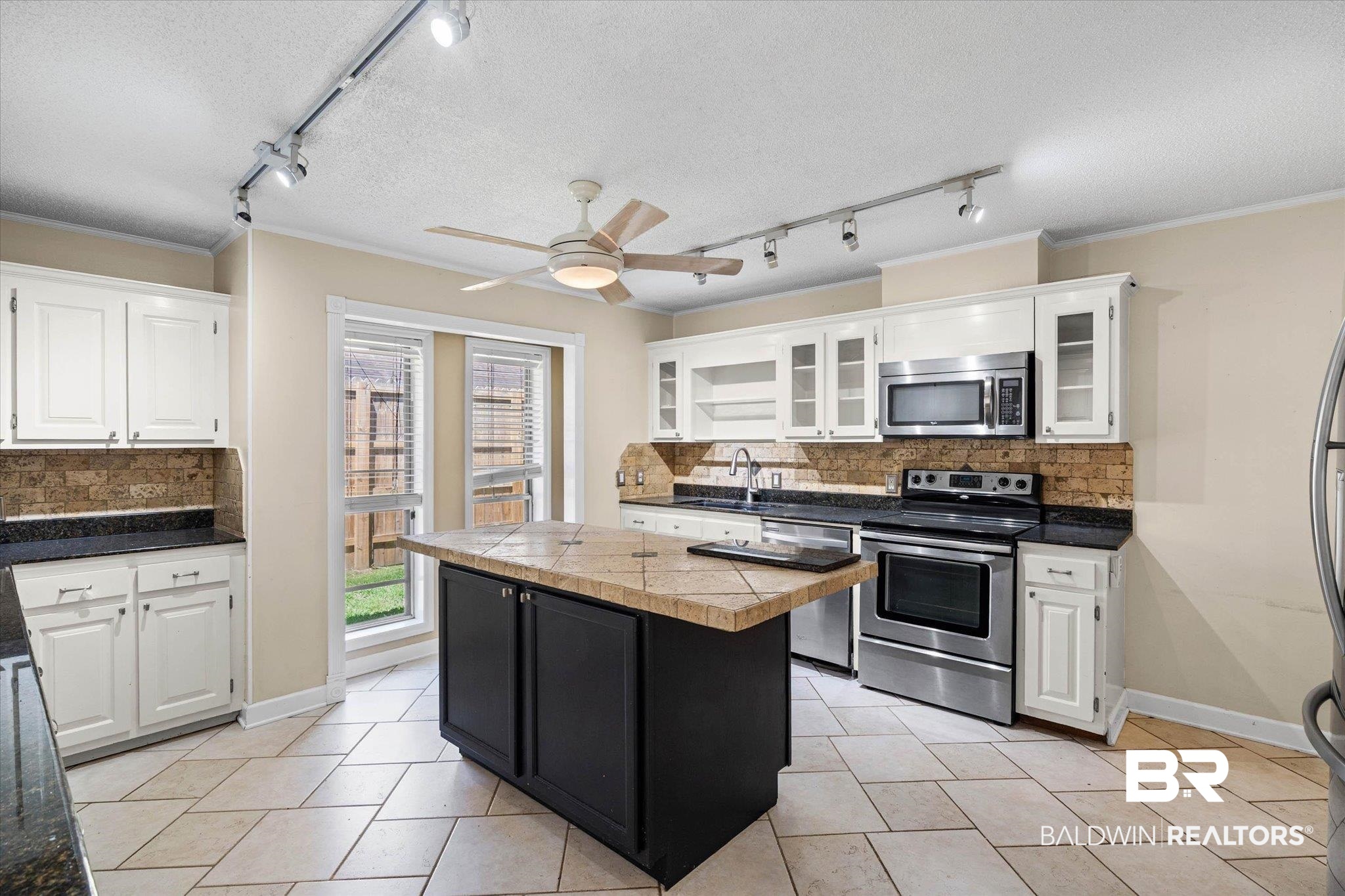 3724 Claridge Road South Mobile, AL 36608 - Photo 8 of 42 Kitchen featuring tasteful backsplash, rail lighting, stainless steel appliances, a kitchen island, and two tone cabinets