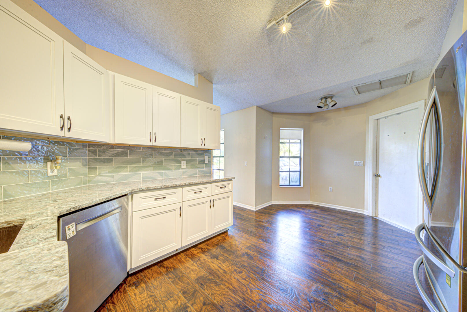 2423 Jaywood Road Titusville, FL 32780 - Photo 13 of 37 a kitchen with granite countertop a stove a sink and white cabinets with wooden floor