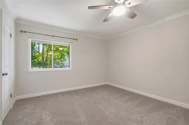 an empty room with a chandelier fan and windows
