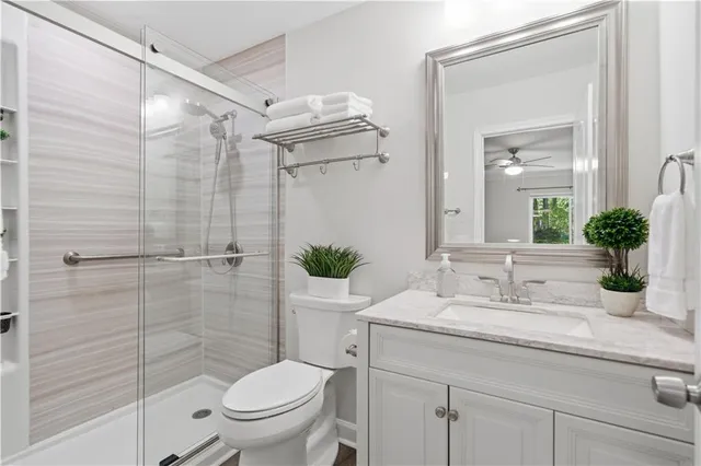 a bathroom with a granite countertop sink a toilet and shower
