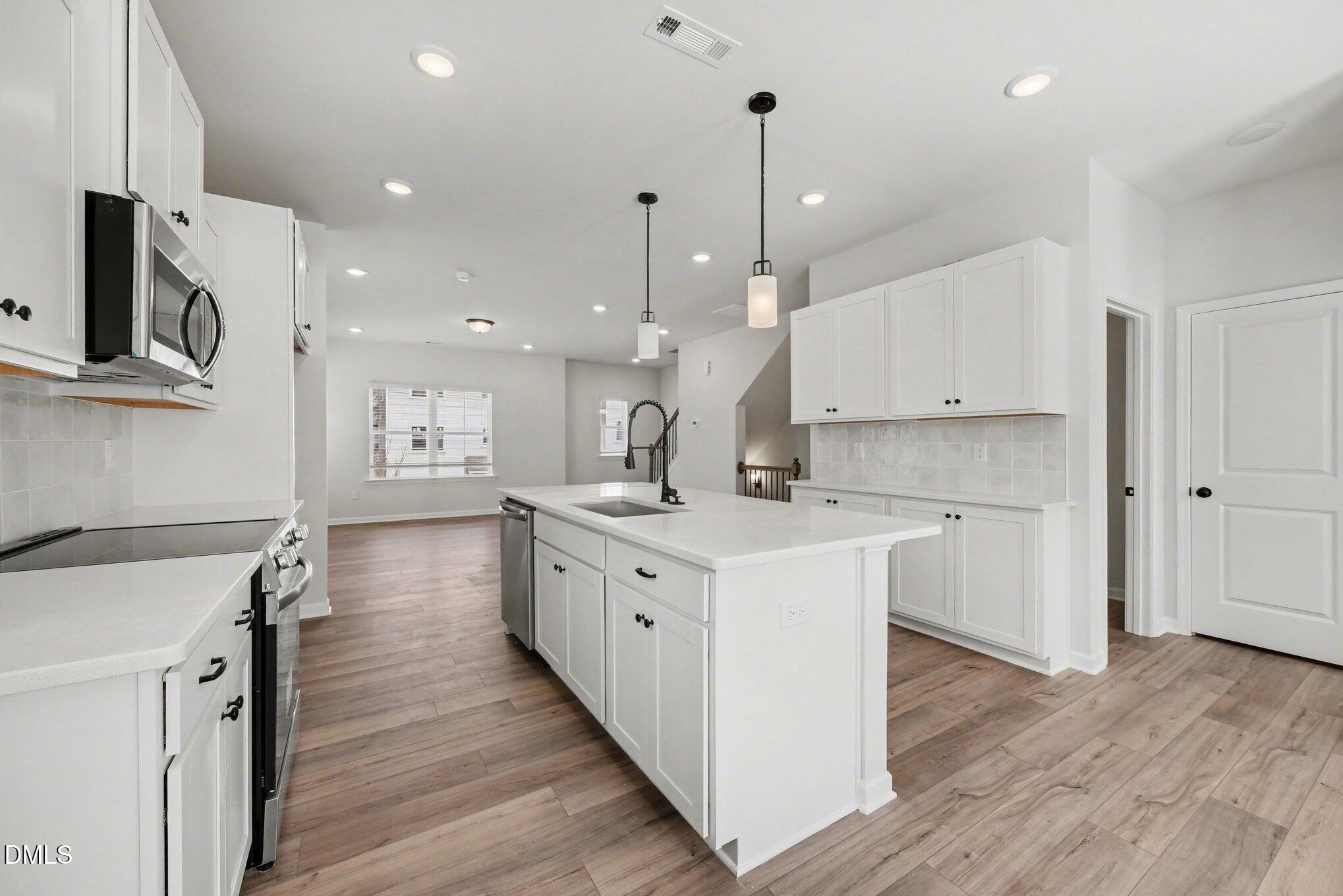 720 Orch Vista Circle Raleigh, NC 27606 - Photo 3 of 28 a large kitchen with stainless steel appliances kitchen island a large counter top and wooden floors