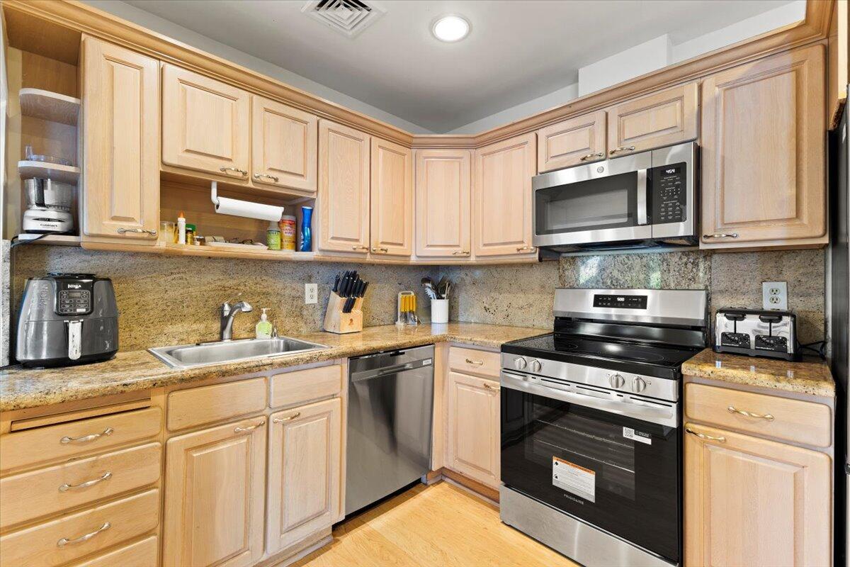 233 Rio Vista Circle, Unit 233 Atlantis, FL 33462 - Photo 11 of 33 a kitchen with stainless steel appliances granite countertop a stove a sink dishwasher and a microwave oven with cabinets