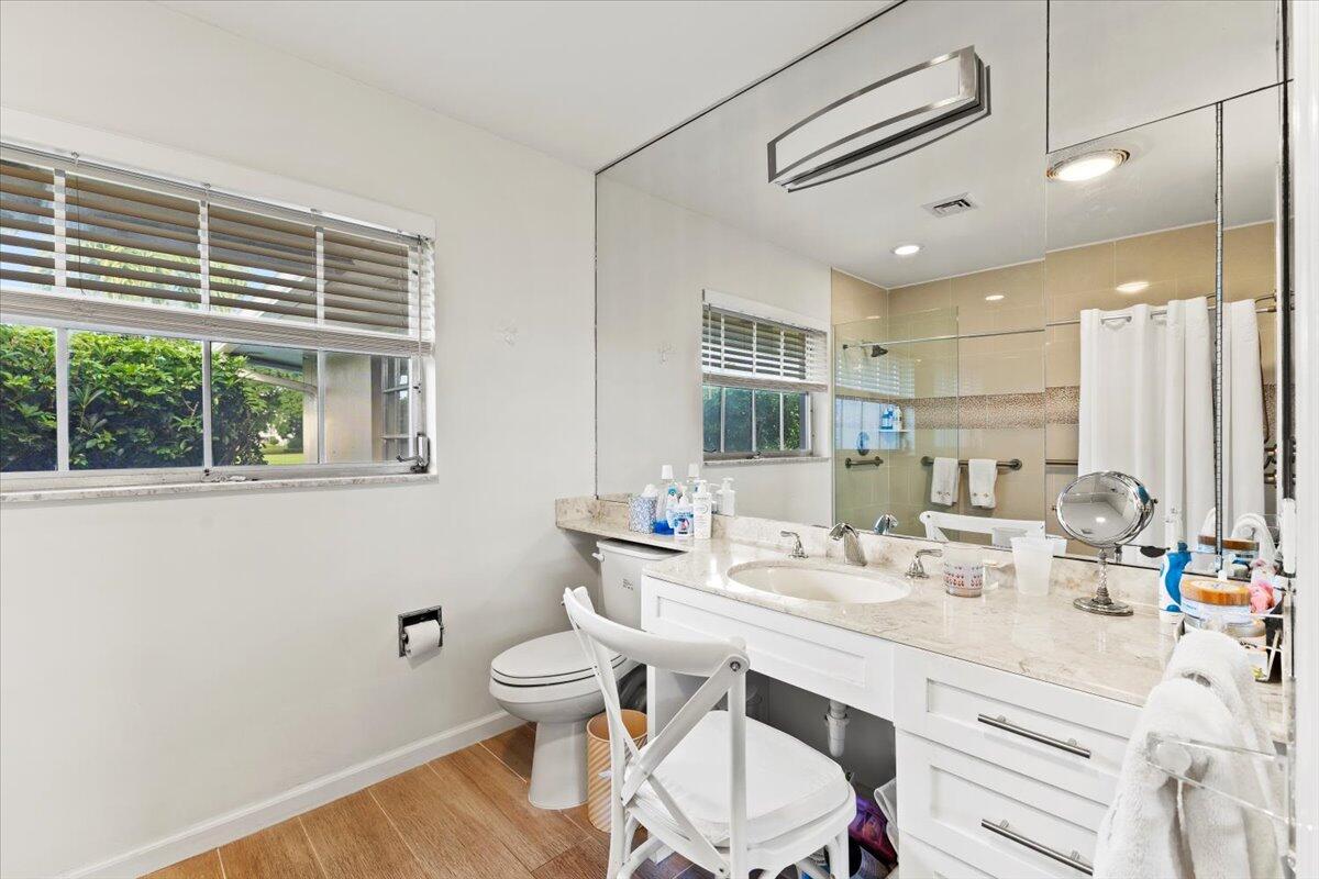 233 Rio Vista Circle, Unit 233 Atlantis, FL 33462 - Photo 17 of 33 a bathroom with a double vanity sink a toilet and a window
