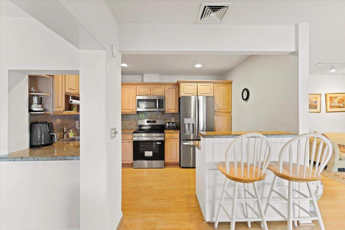 233 Rio Vista Circle, Unit 233 Atlantis, FL 33462 - Photo 4 of 33 a kitchen with stainless steel appliances wooden floor and a refrigerator