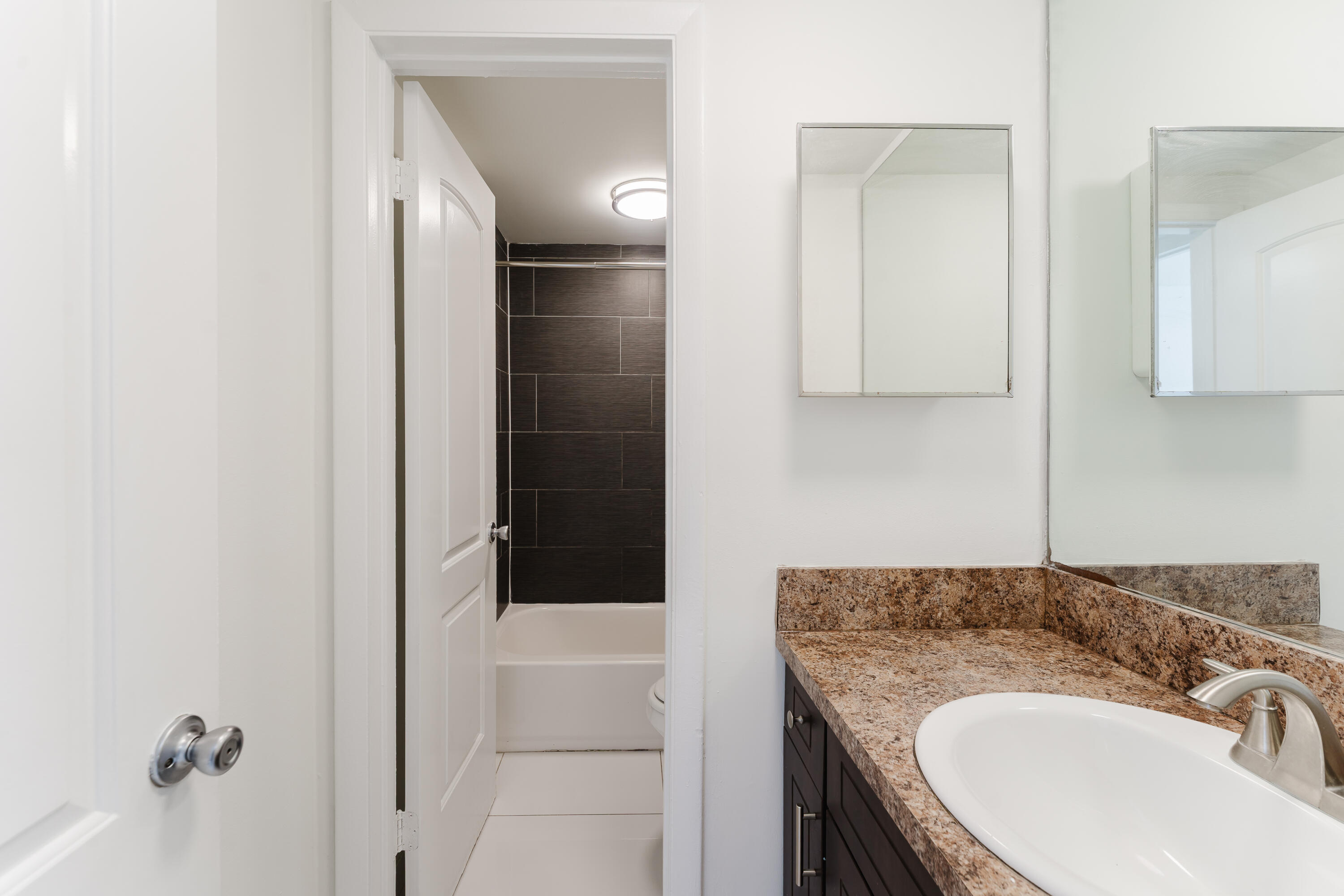 606 Northwest 13th Street, Unit 23 Boca Raton, FL 33486 - Photo 13 of 37 a bathroom with a granite countertop sink a mirror and shower
