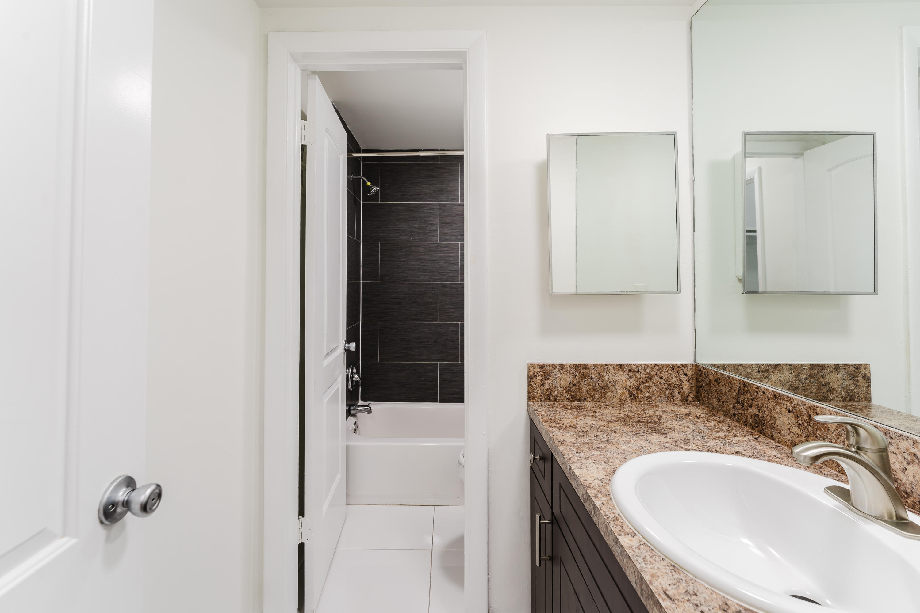 606 Northwest 13th Street, Unit 23 Boca Raton, FL 33486 - Photo 28 of 37 a bathroom with a granite countertop sink a mirror and shower