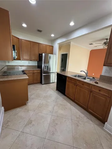 a kitchen with granite countertop a refrigerator and a stove top oven