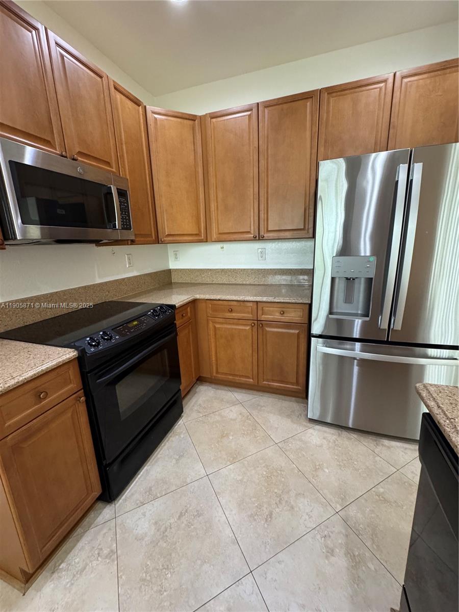 3166 Merrick Terrace, Unit 1705 Margate, FL 33063 - Photo 20 of 41 a kitchen with granite countertop a refrigerator and a stove top oven