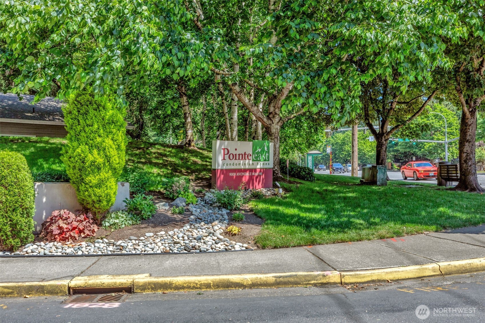 9009 Avondale Road Northeast, Unit D107 Redmond, WA 98052 - Photo 33 of 34 a sign board with flower plants and large trees