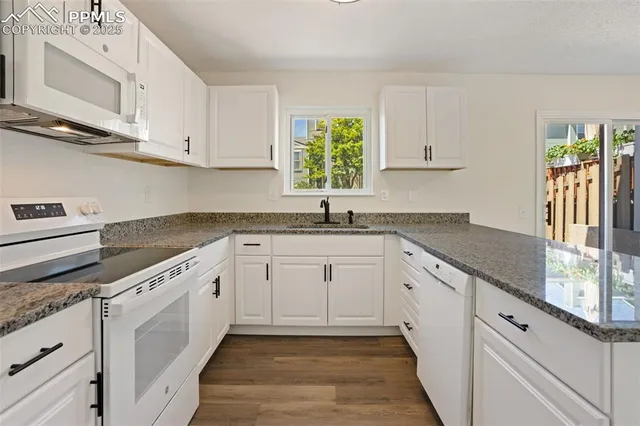 a kitchen with granite countertop white cabinets and white appliances