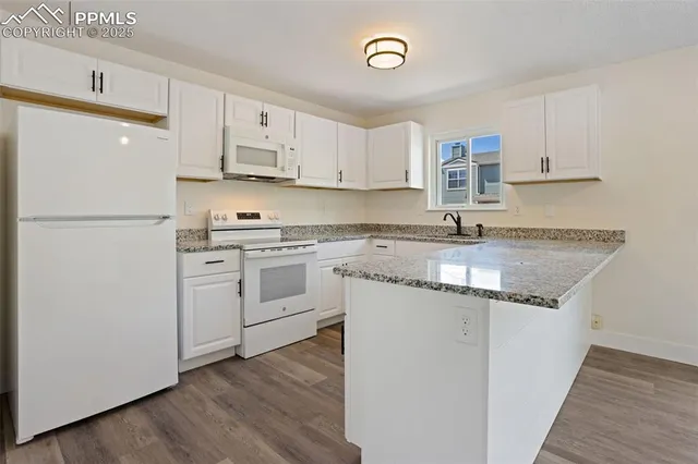 a kitchen with a sink a stove a refrigerator and white cabinets