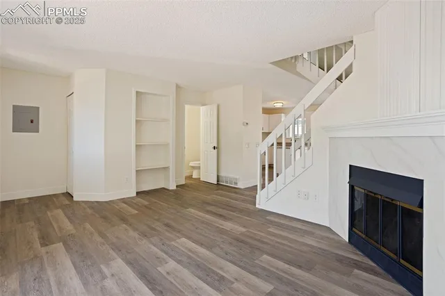 a view of an empty room with wooden floor fireplace and a window