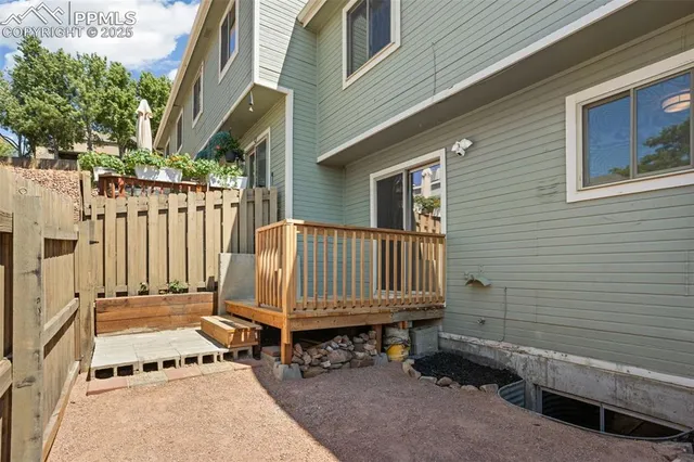 a view of a backyard with a small deck and wooden fence
