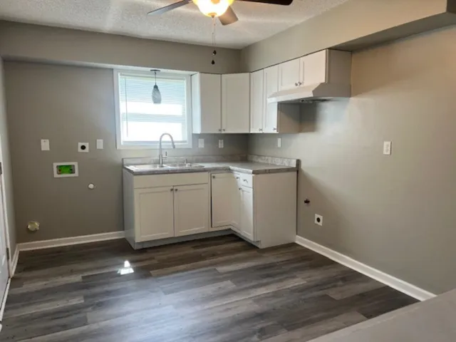 a kitchen with a sink cabinets and wooden floor