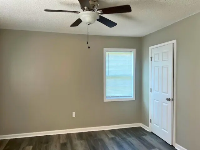 an empty room with wooden floor closet and windows
