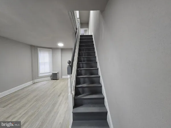 a view of a hallway with wooden floor and a bathroom