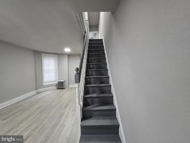 a view of a hallway with wooden floor and a bathroom