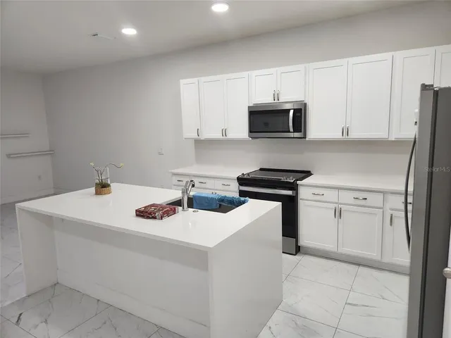 a kitchen with white cabinets sink and stainless steel appliances