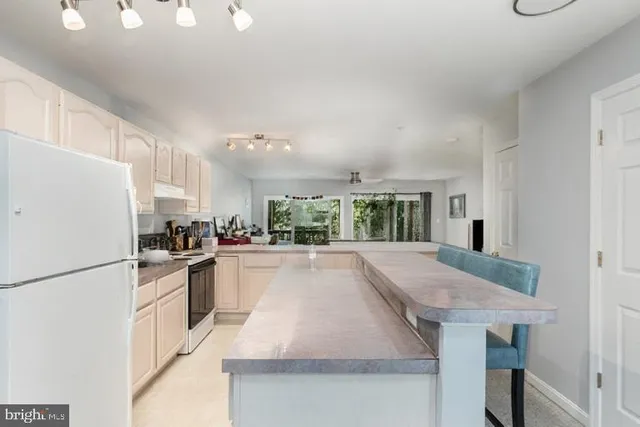 a kitchen with granite countertop a stove a sink dishwasher a refrigerator and a dining table with wooden floor