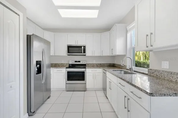 a kitchen with granite countertop a sink a counter top space stainless steel appliances and cabinets