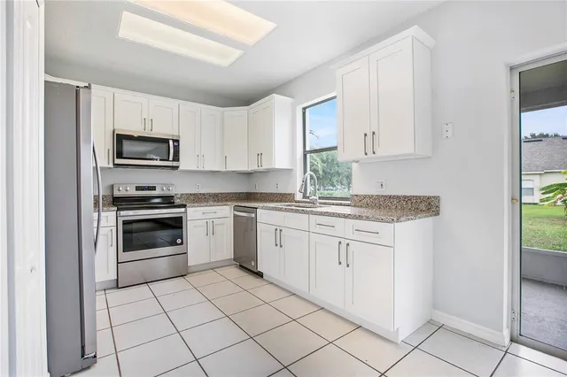 a kitchen with granite countertop white cabinets and stainless steel appliances