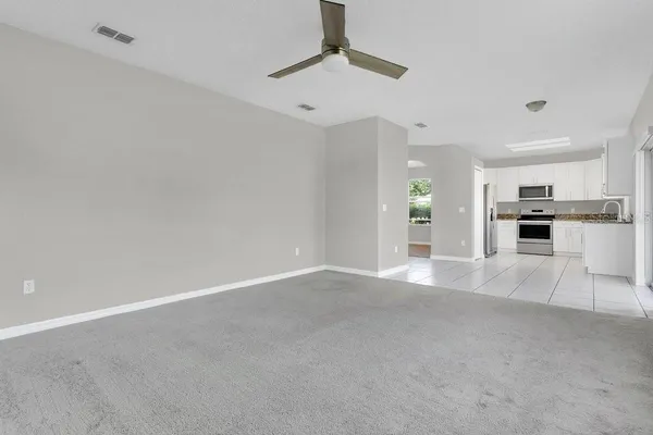 a view of an empty room with kitchen and window