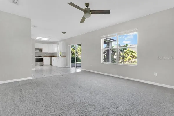 an empty room with windows and ceiling fan