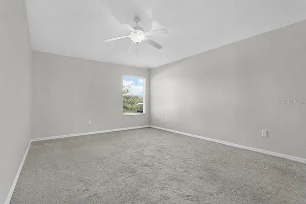 an empty room with windows and fan