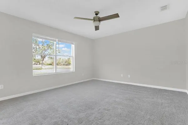 an empty room with a window and a ceiling fan