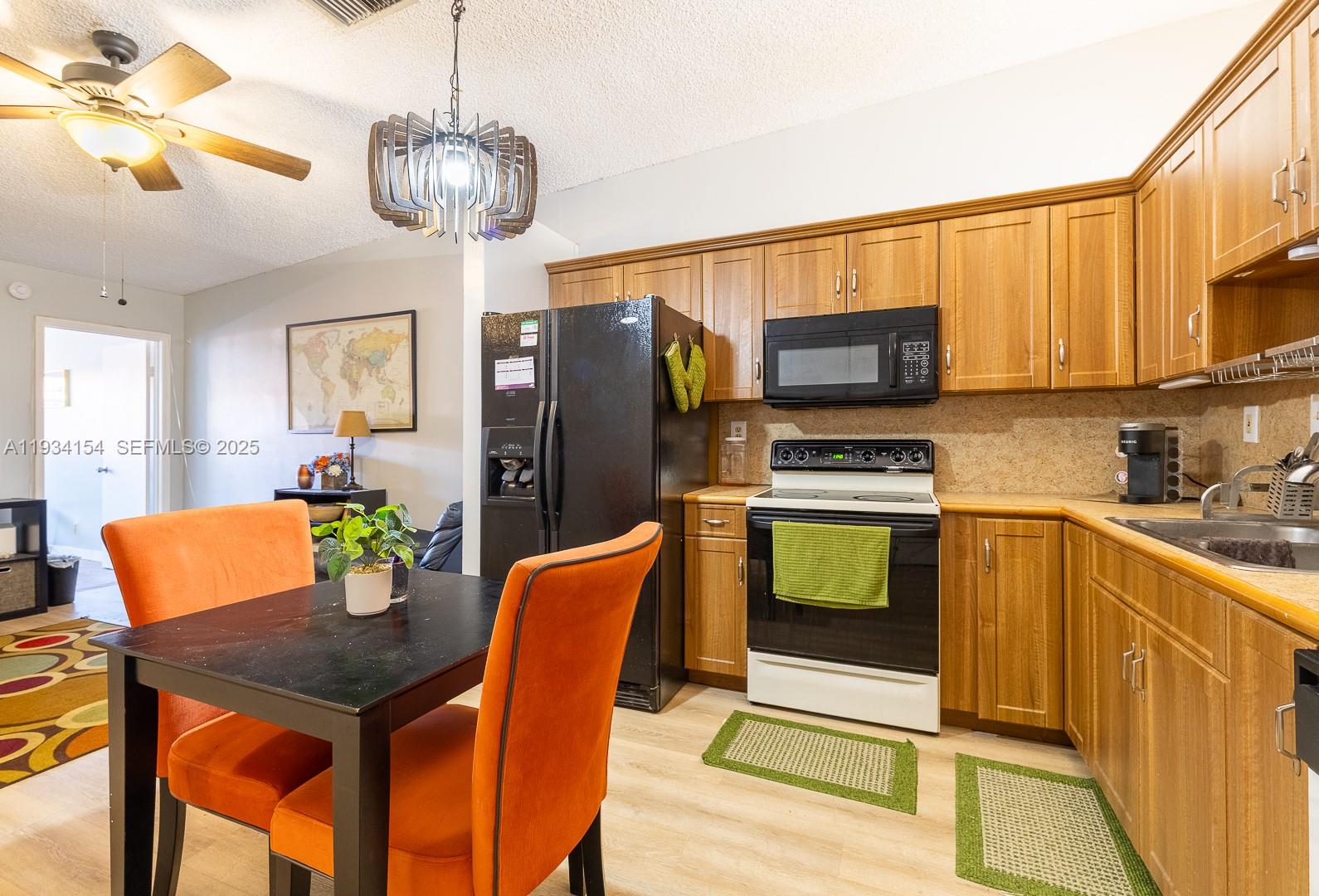 6491 Northwest 190th Terrace Hialeah, FL 33015 - Photo 13 of 28 a kitchen with stainless steel appliances granite countertop a refrigerator a stove a sink dishwasher a dining table and chairs with wooden floor