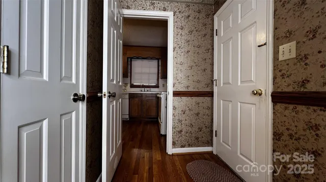 a view of an empty room with wooden floor fireplace and a window