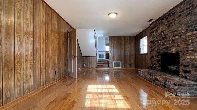 a view of a hallway with wooden floor and living room