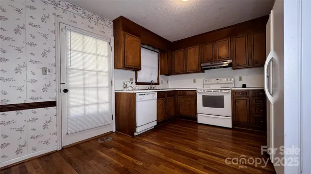 a kitchen with stainless steel appliances granite countertop a refrigerator a stove top oven a sink and dishwasher with wooden floor