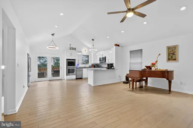 a kitchen with stainless steel appliances kitchen island granite countertop a stove a sink dishwasher a refrigerator and white cabinets with wooden floor
