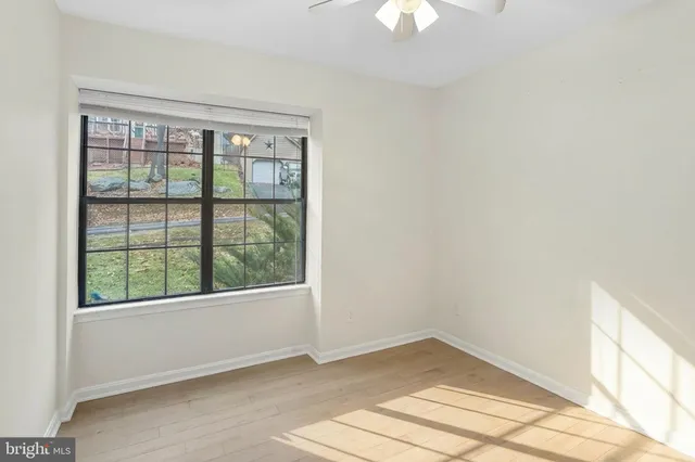 a view of an empty room with window and wooden floor