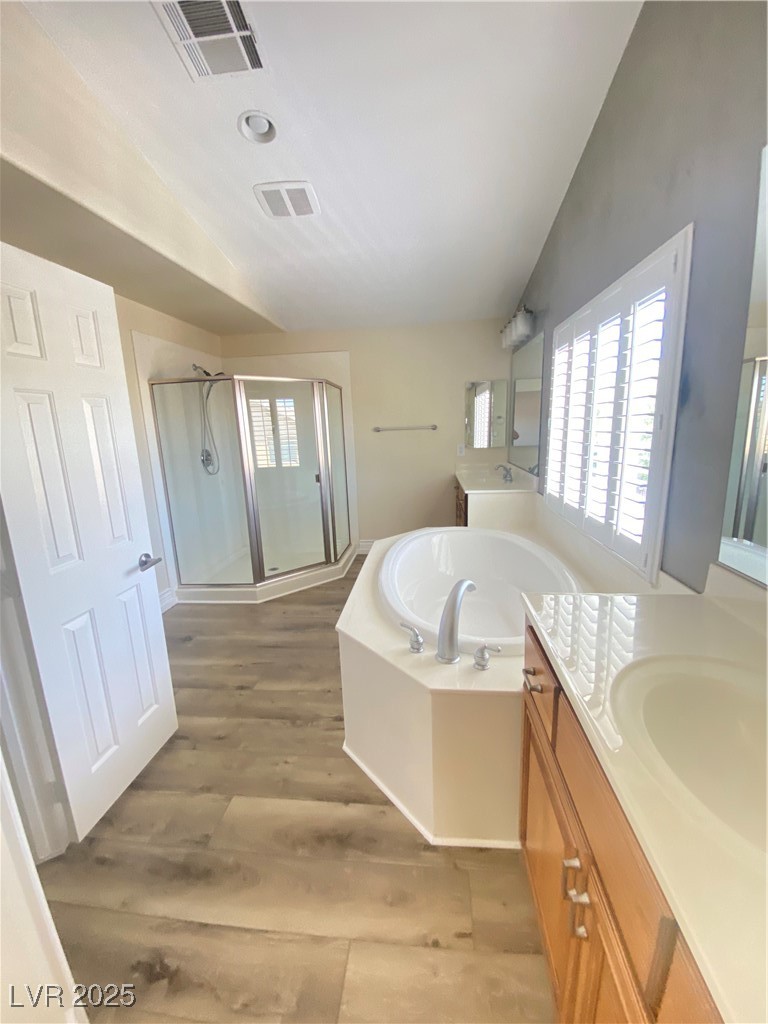172 Tall Ruff Drive Las Vegas, NV 89148 - Photo 33 of 94 Full bath featuring vaulted ceiling, vanity, a shower stall, a garden tub, and wood finished floors