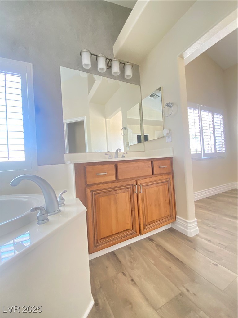 172 Tall Ruff Drive Las Vegas, NV 89148 - Photo 34 of 94 Bathroom featuring vanity, a garden tub, healthy amount of natural light, and wood finished floors