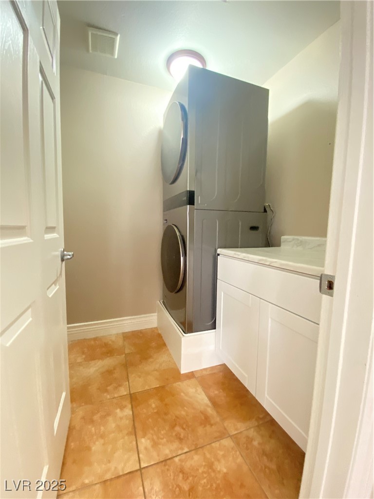 172 Tall Ruff Drive Las Vegas, NV 89148 - Photo 44 of 94 Clothes washing area featuring visible vents, baseboards, light tile patterned flooring, cabinet space, and stacked washer and dryer