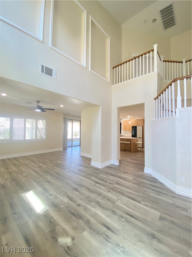 172 Tall Ruff Drive Las Vegas, NV 89148 - Photo 9 of 94 Great room with kitchen in the background, a ceiling fan, baseboards, and a towering ceiling