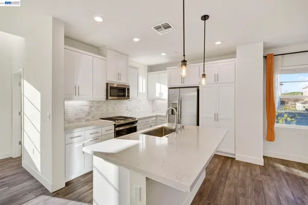 a kitchen with stainless steel appliances granite countertop a sink a refrigerator and a stove