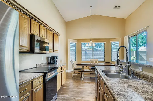 a kitchen with stainless steel appliances granite countertop a refrigerator a sink and a microwave