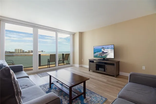 a living room with furniture a flat screen tv and a floor to ceiling window