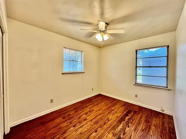 a view of empty room with wooden floor and fan