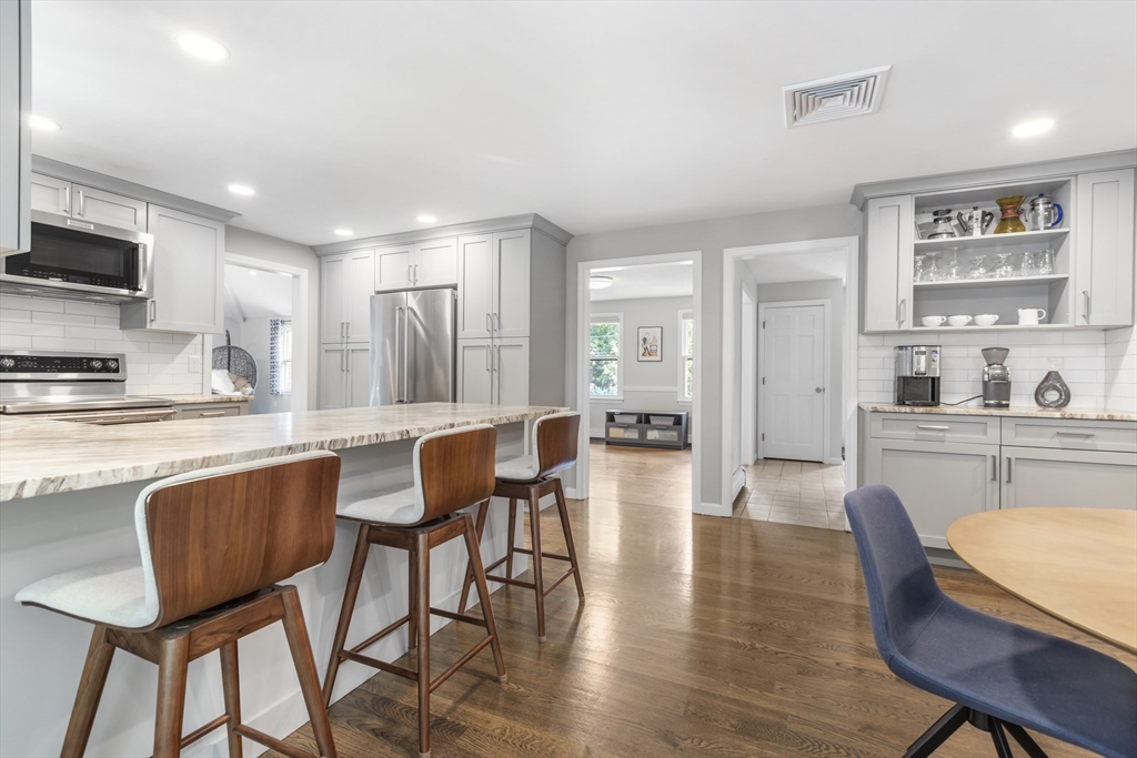 61 Sunset Drive Milford, MA 01757 - Photo 8 of 42 a kitchen with stainless steel appliances kitchen island granite countertop a dining table chairs and a refrigerator