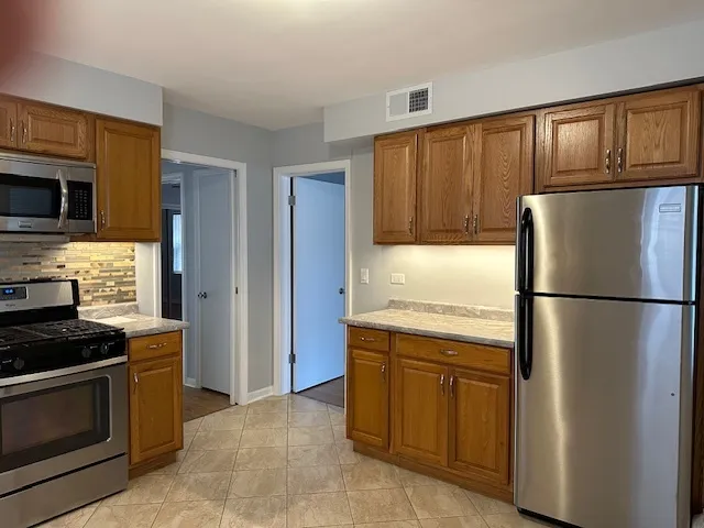 a kitchen with stainless steel appliances granite countertop a refrigerator and a stove top oven